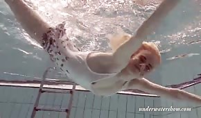 Une fille blonde mince nage sous l'eau