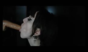Une fille aux cheveux noirs suce une bite en caoutchouc